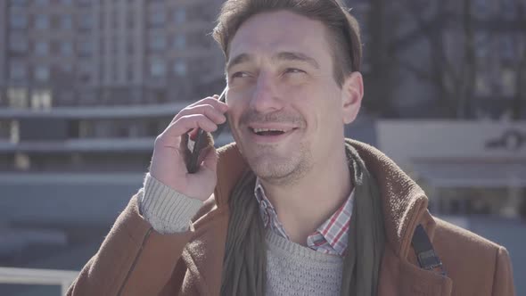 Portrait of Successful Handsome Confident Man in Brown Coat Standing in the City Street Talking