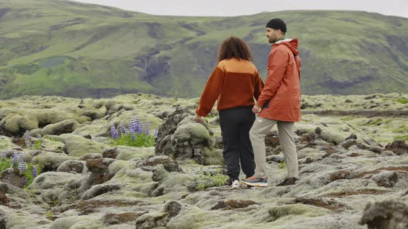 Couple Hiking over Rocks in Moss Covered Landscape