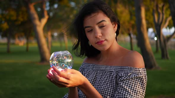 A beautiful sorceress holding a magic glowing crystal ball with an enchanting and mysterious look.