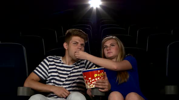 Great Movie! Young Couple Feeding Each Other at the Cinema
