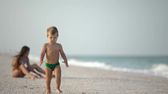 Older Sister Playing with Younger Brother Aground Near the Shore on Summer Vacation