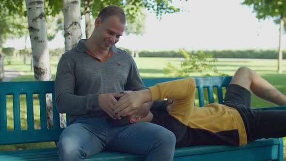 Happy Gay Lying on Boyfriend's Lap on Park Bench