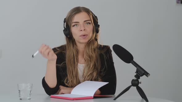 Young blond woman Records a podcast, lecture, or webinar on a dictaphone.