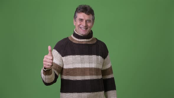 Mature Handsome Man Wearing Turtleneck Sweater Against Green Background