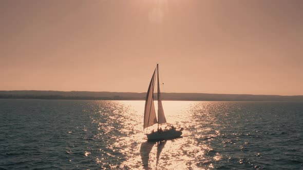 Sailing Yacht Sails on the Open Sea on a Windy Day at Sunset Aerial View