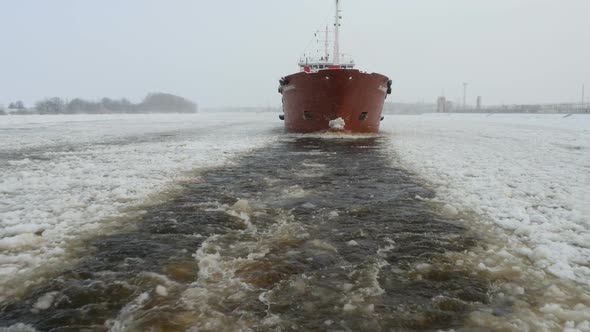 Frozen Water. Shipping, Nose Of Ship Moving In Winter Water, Snow Falling, Oil Tanker Moves Boats.