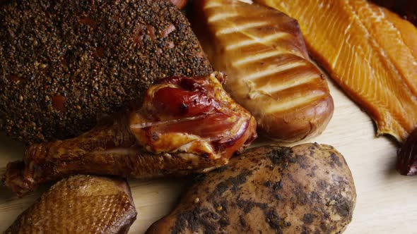 Rotating shot of a variety of delicious, premium smoked meats on a wooden cutting board