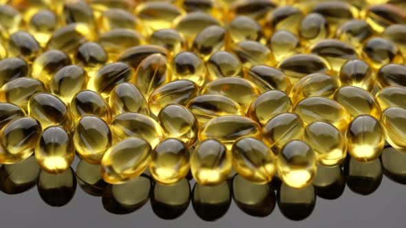 Omega 3 gold oil capsules close up, rotation. Supplement organic vitamins in softgel capsules