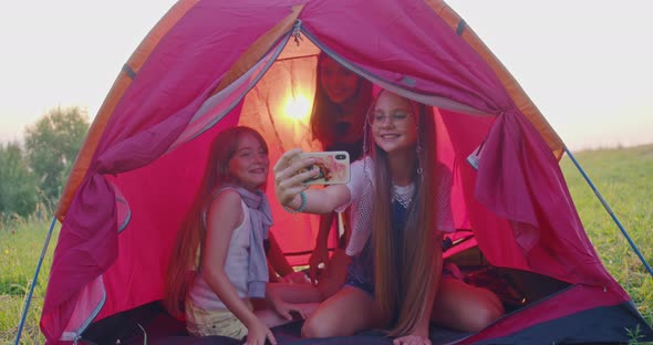 Four Teenage Girls Making Selfie in Camp Tent in Mountains