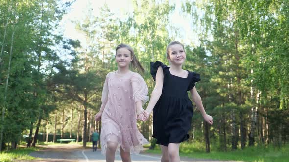 Couple of Girls Runs Together on Park Pathway Joining Hands