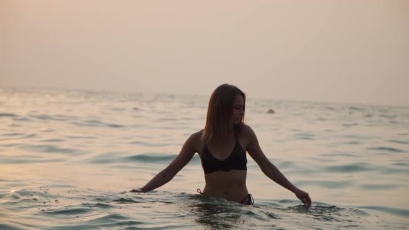 Girl Bathes in the Sea Against the Backdrop of the Sunset