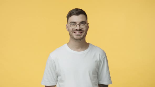 Studio Portrait Young Caucasian Guy in White Tshirt Glasses Smiling Pleased Hearing Good Idea Nod in