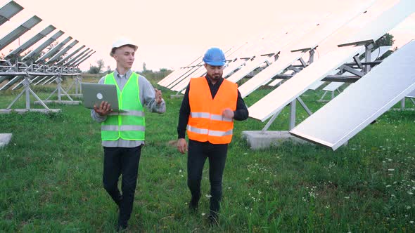 Two Technicians Walking Through the Field of Solar Panels.