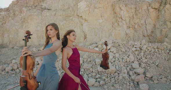 Female Musicians in Blowing Dresses Perform Playing Violin and Posing on Nature
