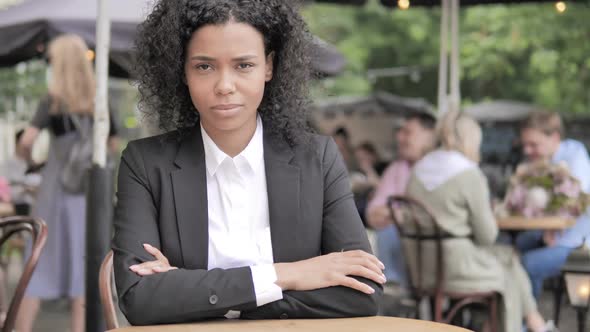 Smiling African Businesswoman Sitting in Outdoor Cafe