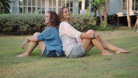 Happy Lesbian Couple Sitting with Their Backs To Each Other