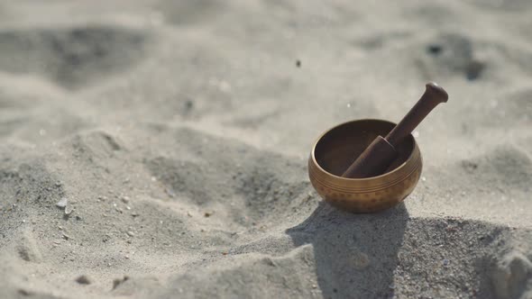 Bronze Tibetan Singing Bowl for Meditation on the Sandy Sea Beach