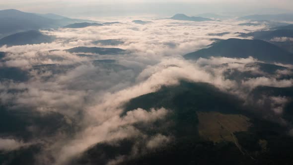 Low clouds and morning mists over mountain slopes at sunrise