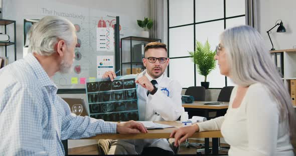 Doctor Showing Results-of X-ray Scan to Senior Satisfied Couple which Giving High Five