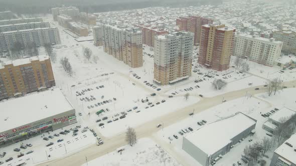 Residential Area and Snowy City Road with Slow Moving Cars in Winter