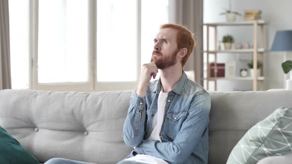 Pensive Man Thinking While Sitting on Sofa in Creative Space