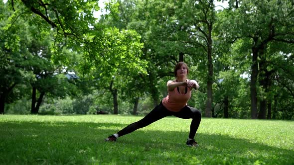 Girl Doing Squats in the Park on the Grass