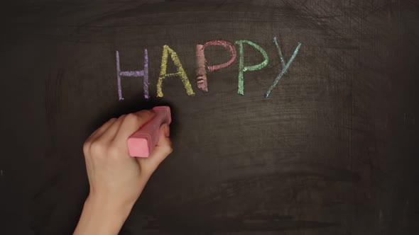 Human Hand Writes Happy Easter on Blackboard with Colored Chalk alt