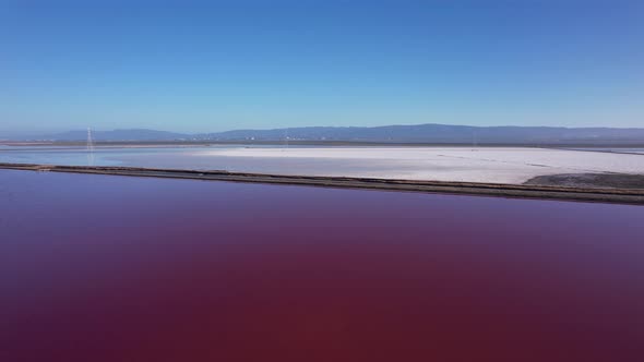 Flying diagonal over maroon colored salt ponds in East bay area, Northern California