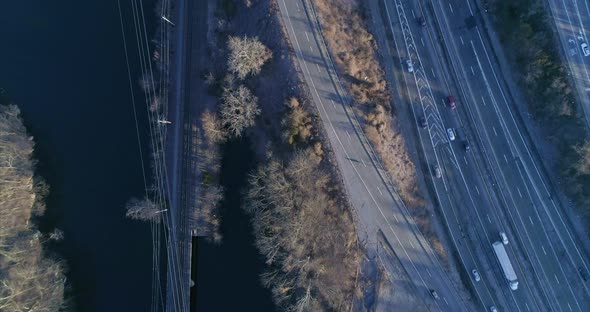 Top Down View of Cars Driving on a Highway and Train Tracks Over River