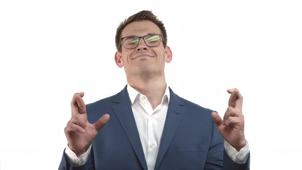 Handsome Hopeful Male Entrepreneur in Blue Suit and Glasses Feeling Optimistic While Making Wish