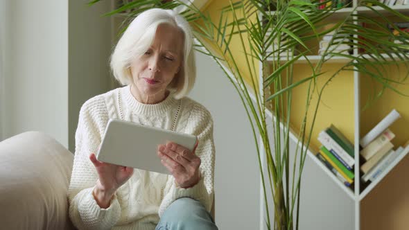 Elderly Woman Using a Computer Tablet, Looking at the Screen, Elderly Older Woman with Gray Hair