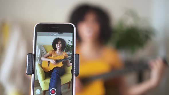 Young Woman at Home Singing and Playing Guitar for Followers Spbd