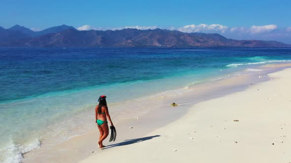 Girls sunbathing on beautiful coastline beach adventure by blue green ocean with white sand backgrou