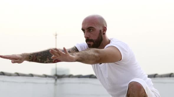 Man Performs Strong Yoga Pose With One Leg While His Arms Are Suspended In Air