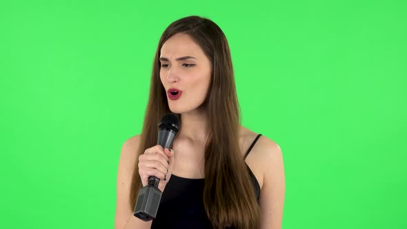 Attractive Girl Sings Into a Microphone and Moves To the Beat of Music