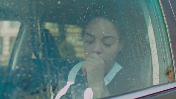 Sad Woman Looking Through Car Window with Raindrops