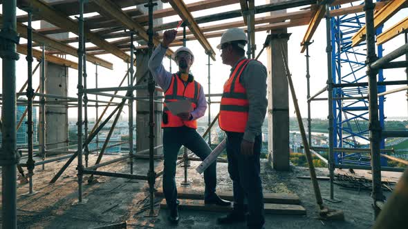 Male Engineers Are Planning Constructions Among the Scaffolding alt