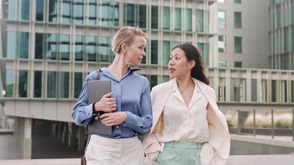 Stylish Business Women Walking and Talking Outdoors the Workplace Caucasian and Asian Female