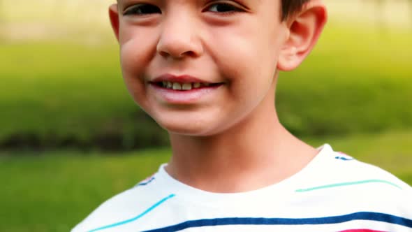 Smiling boy waving his hand in park on a sunny day