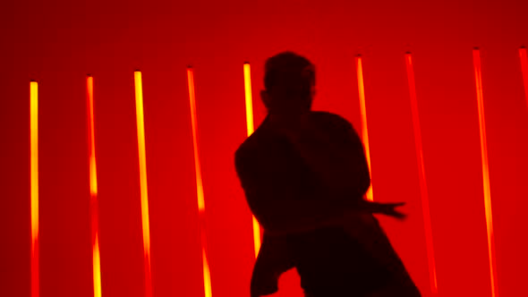 Emotional Performance of a Break Dancer in a Dark Studio Against a Backdrop of Bright Red and Yellow