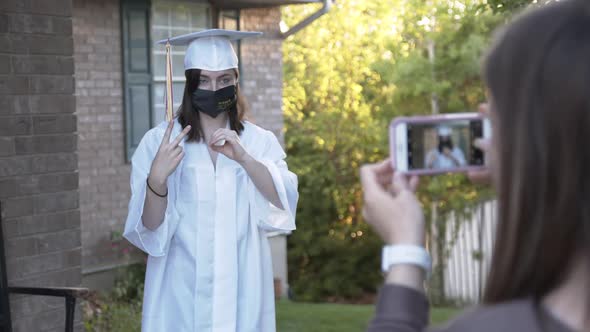 High school girl wearing cap and gown with face mask 2020