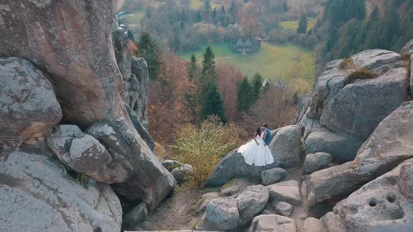 Newlyweds Stand on a High Slope of the Mountain, Groom and Bride, Arial View