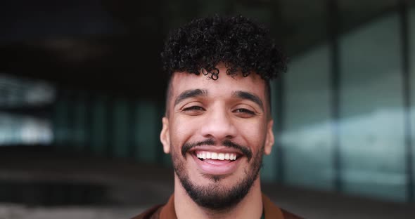 Young latin man smiling on camera outdoor