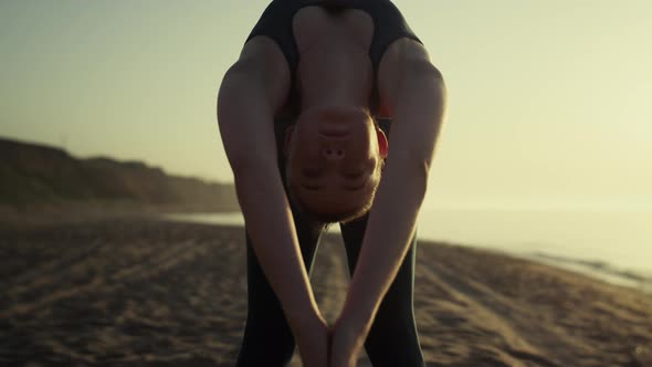 Sexy Girl Practicing Yoga on Sandy Beach Against Hills and Blue Sky Outside