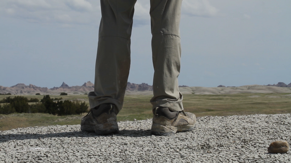Hiker walks past camera and pauses - legs and boots visible - Badlands National Park, South Dakota