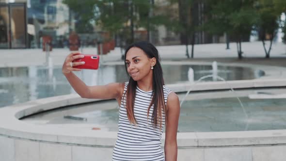 Cheerful African Girl Taking Selfie in Front of Fountains