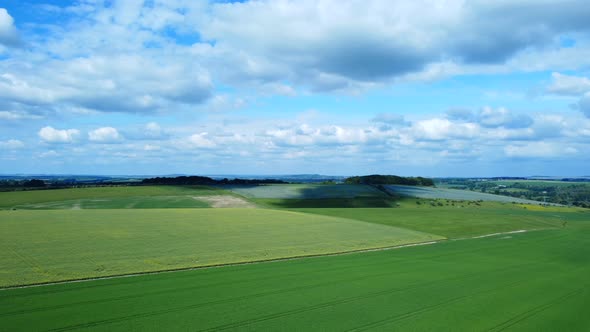 Static aerial view of green farm crops in Salisbury Plains with clouds in England