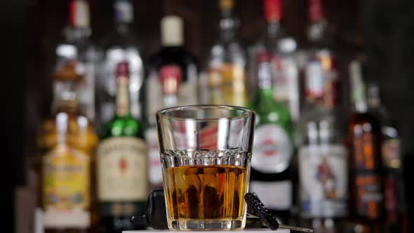 A Man with a Glass of Whiskey in a Bar Car Keys are on the Bar Counter