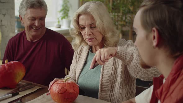 An Old Lady Learns to Carve a Pumpkin for Halloween with Her Family