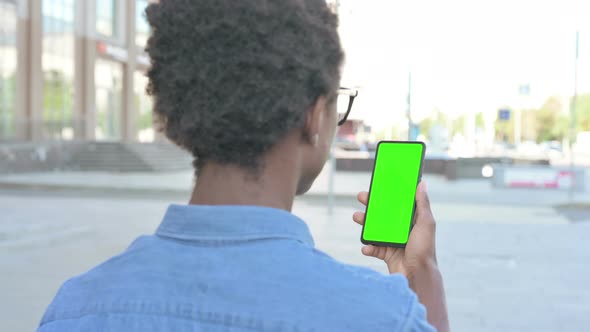 Young African Man Using Smartphone with Green Screen Outdoor